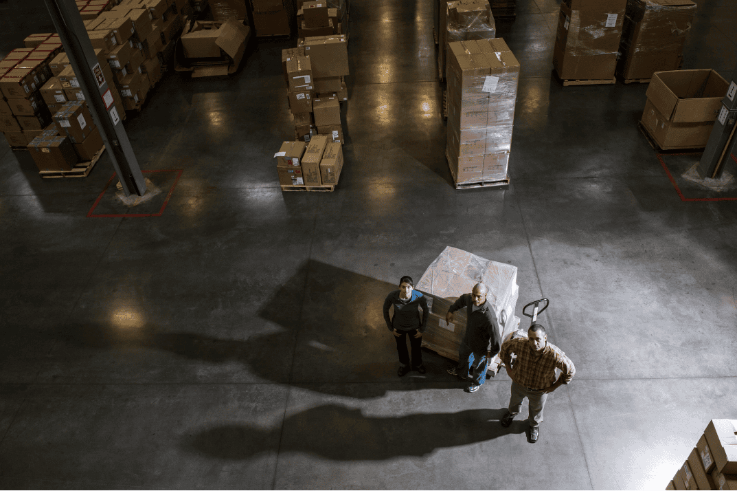 a group three standing in a warehouse looking up in the camera